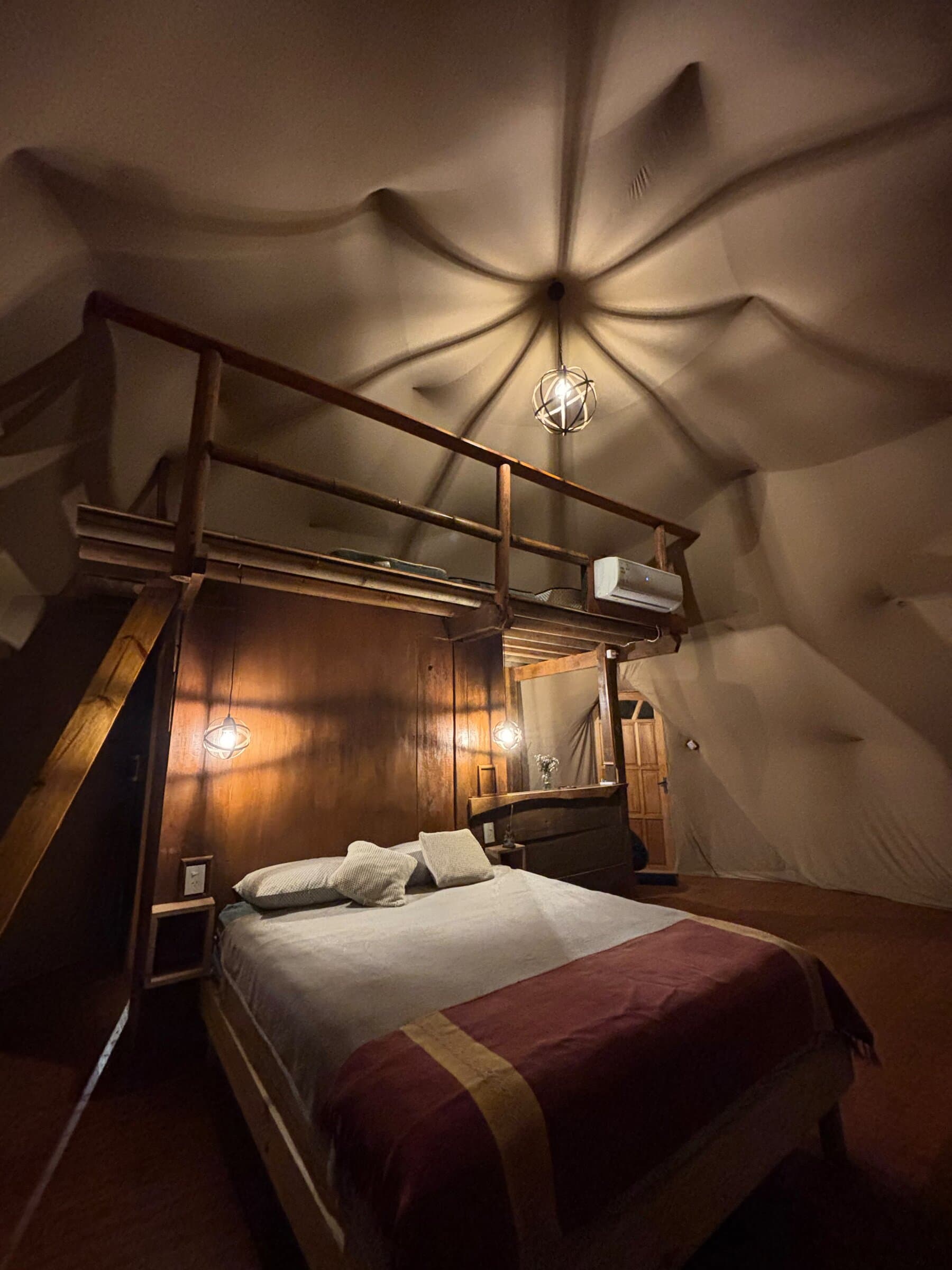 Domo de noche con el altillo de madera sobre la cama y las lámparas encendidas