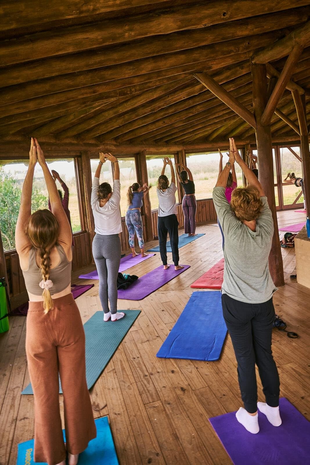 Grupo practicando yoga de pie con los brazos arriba dentro del templo