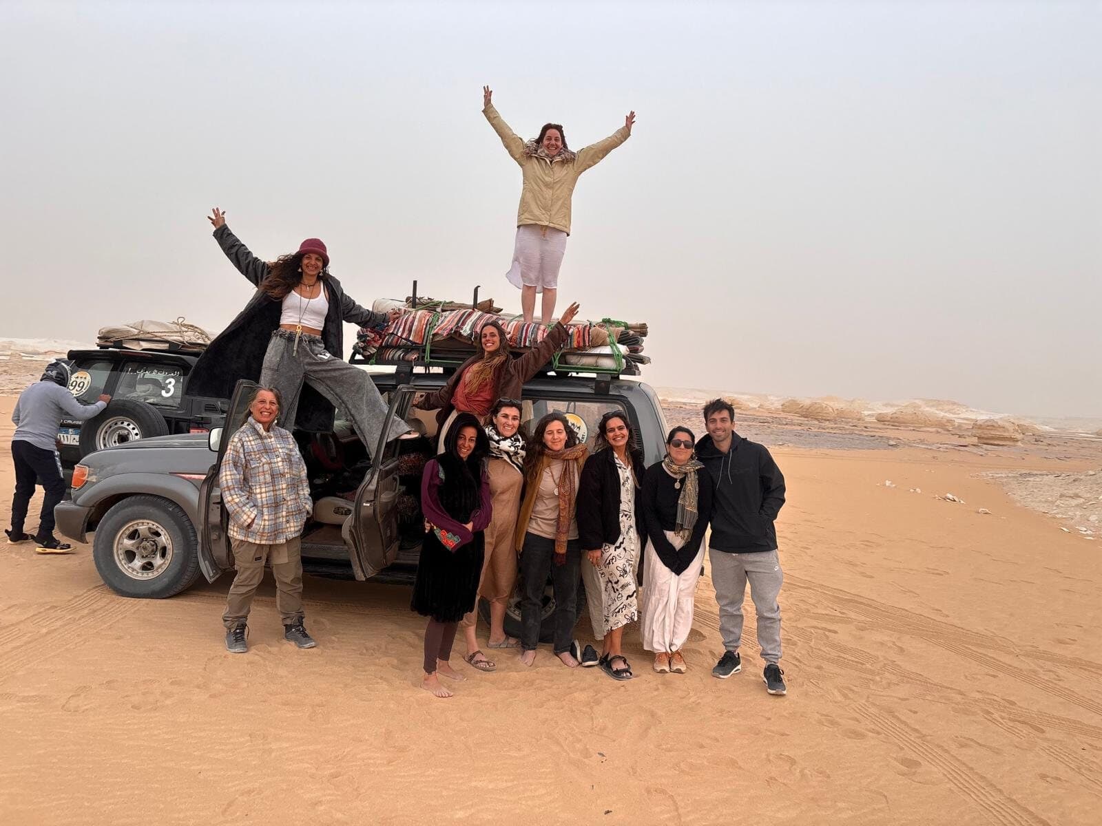 El grupo posando junto a los jeeps cargados en el desierto blanco