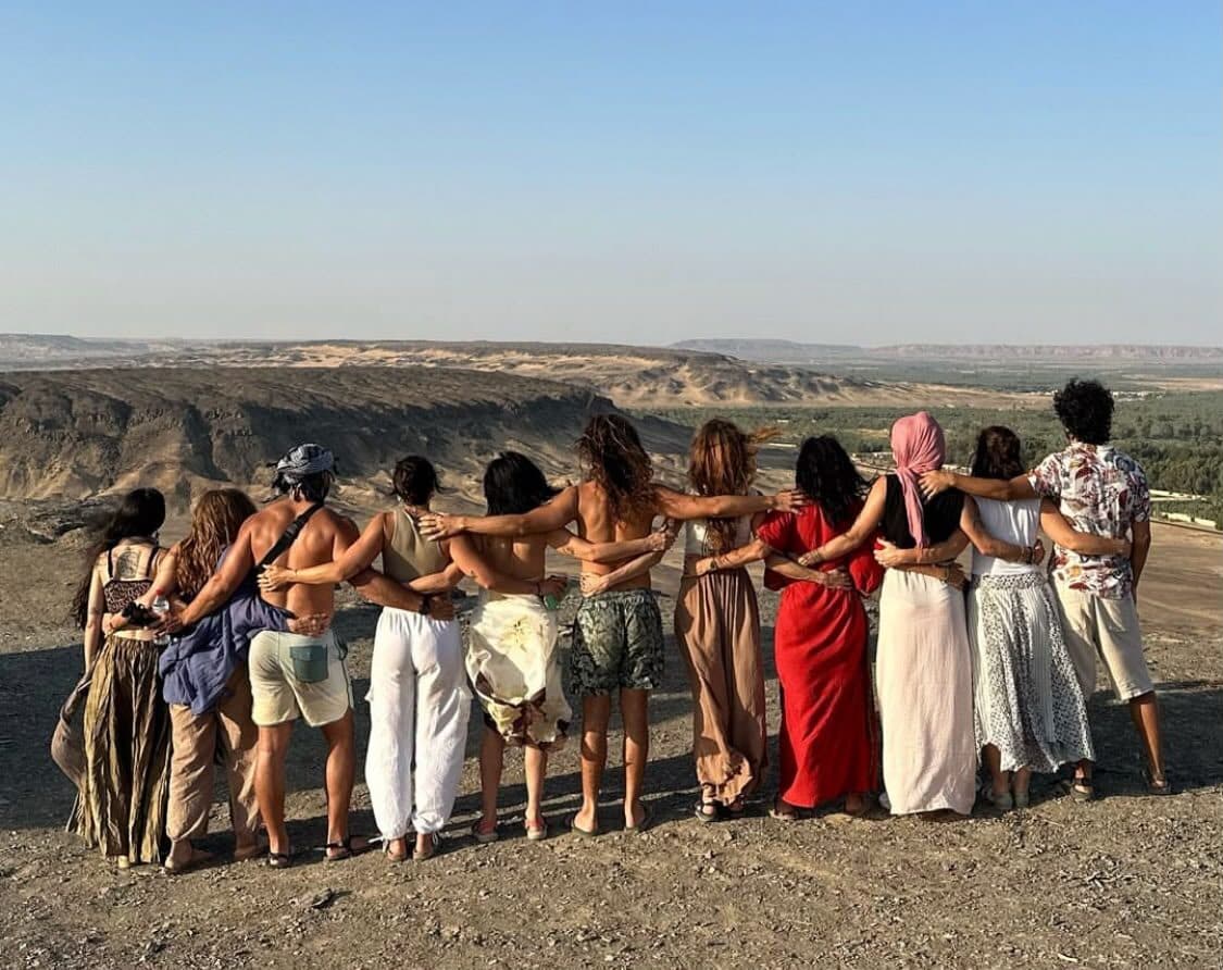 El grupo entero abrazado de espaldas mirando el valle desde lo alto del desierto