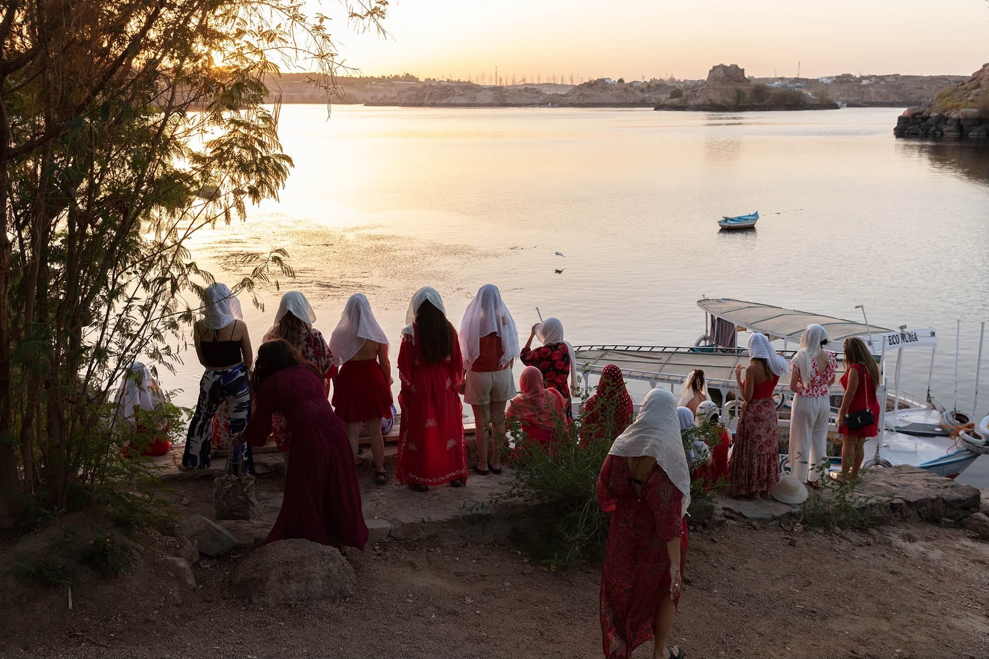 Procesión del grupo bajando hacia el Nilo al atardecer, con los velos puestos