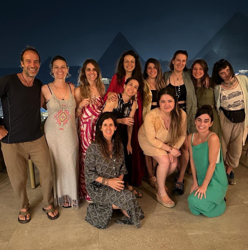 El grupo completo posando de noche con las pirámides de Giza detrás