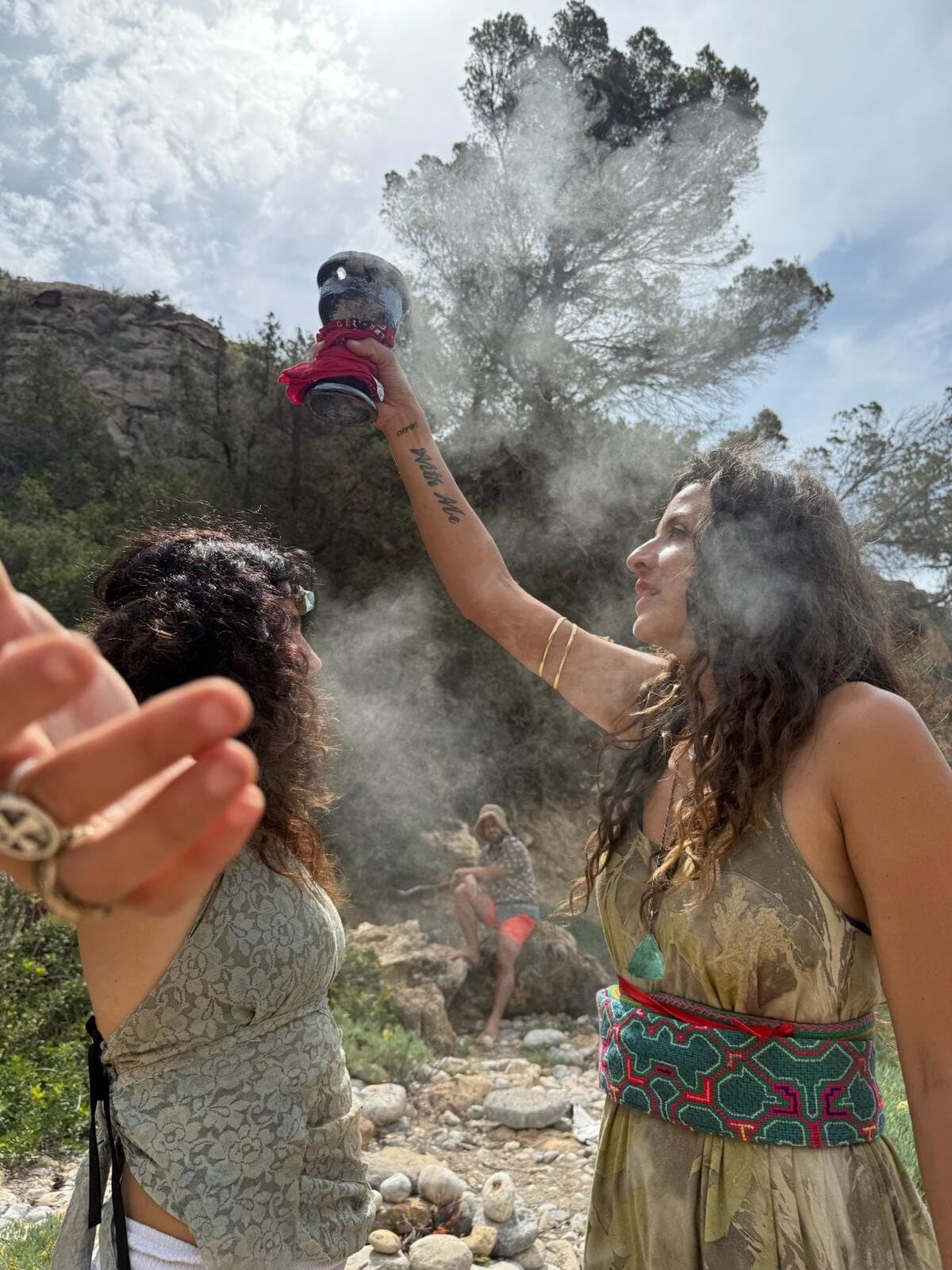 Mujer levantando un sahumador humeante mientras otra recibe el humo con los ojos cerrados